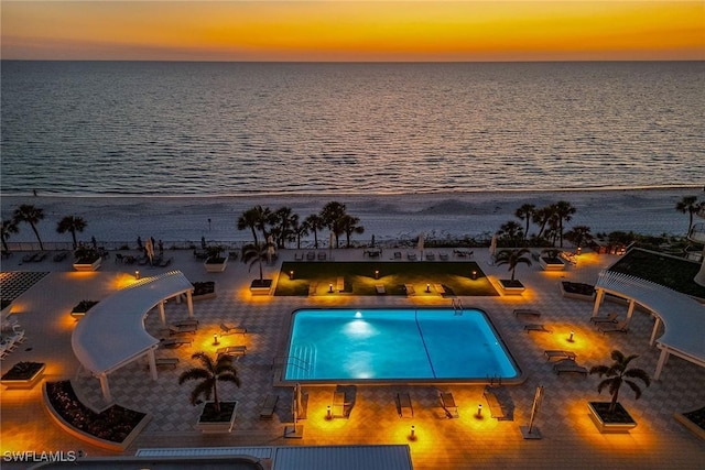 pool at dusk with a view of the beach and a water view