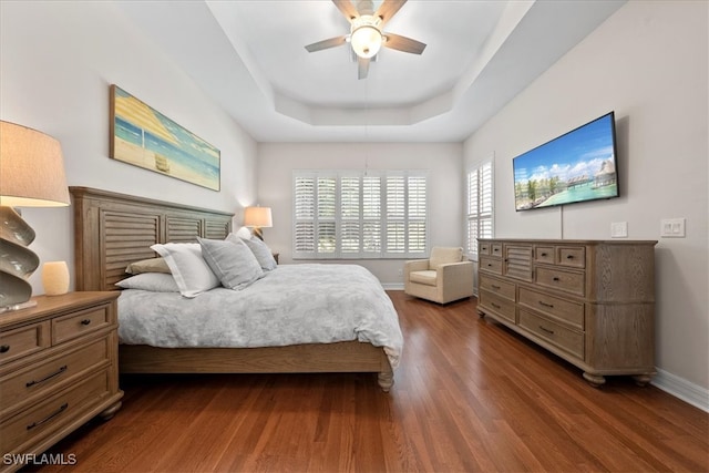 bedroom featuring ceiling fan, a raised ceiling, and dark hardwood / wood-style flooring