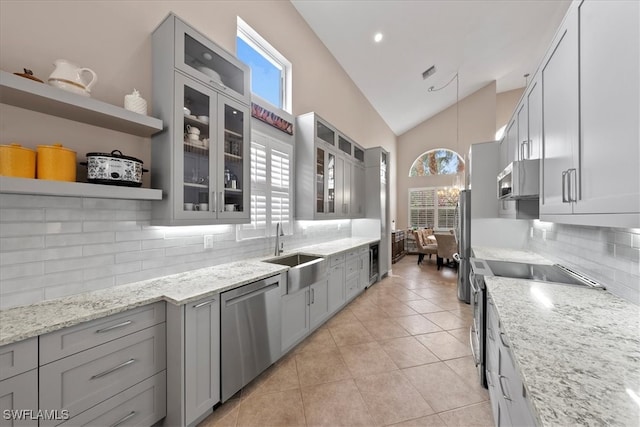 kitchen with a wealth of natural light, pendant lighting, vaulted ceiling, and stainless steel appliances