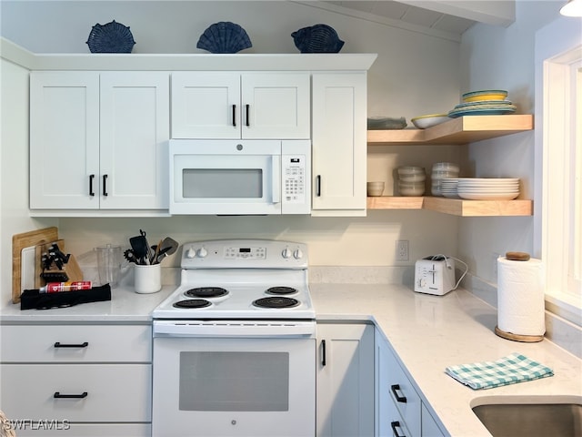 kitchen with vaulted ceiling with beams, light stone counters, white cabinets, and white appliances