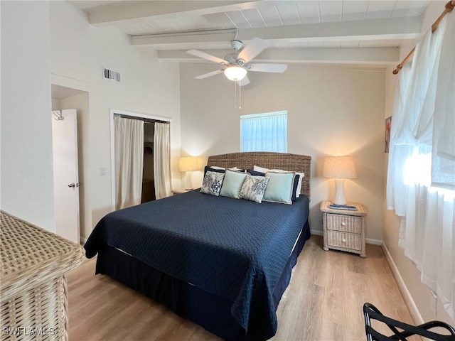 bedroom with multiple windows, ceiling fan, vaulted ceiling with beams, and light wood-type flooring