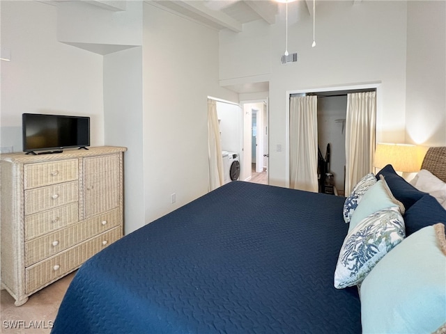 bedroom with beam ceiling, a towering ceiling, washer / clothes dryer, and carpet floors