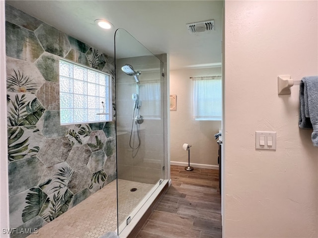 bathroom with tiled shower and hardwood / wood-style flooring