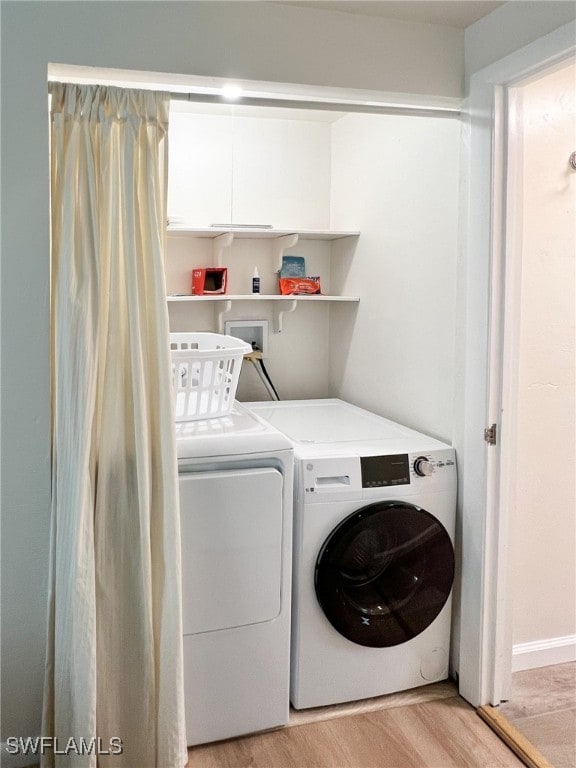 clothes washing area with light hardwood / wood-style floors and washing machine and dryer