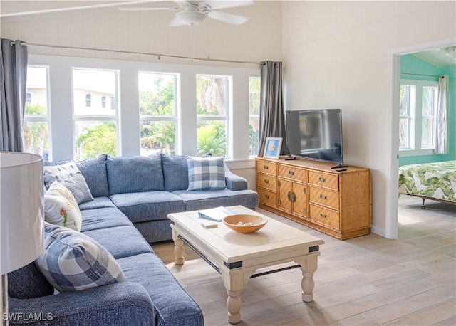 living room with ceiling fan, vaulted ceiling, and light hardwood / wood-style flooring