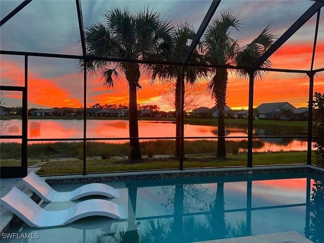 pool at dusk with a water view and glass enclosure