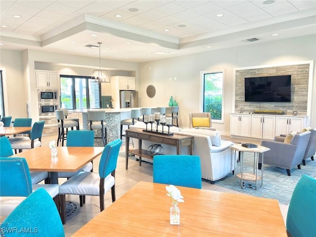 tiled dining space featuring a raised ceiling and ornamental molding