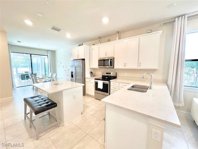 kitchen with a kitchen breakfast bar, a kitchen island, sink, and appliances with stainless steel finishes