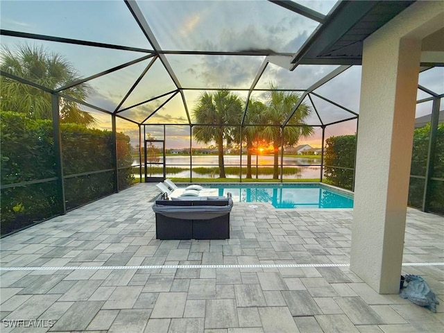 pool at dusk with a lanai, a water view, and a patio