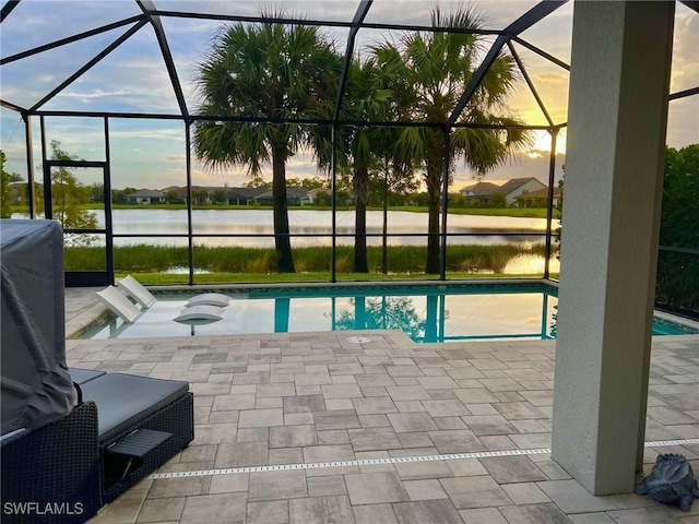 pool at dusk featuring a water view, a patio, and a hot tub