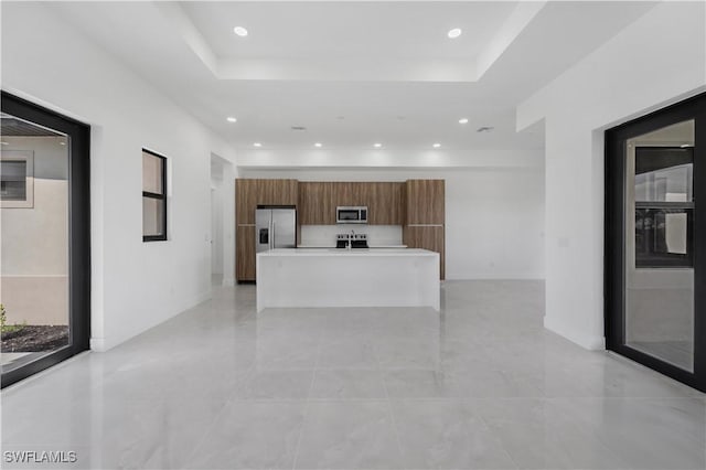 kitchen featuring brown cabinets, light countertops, appliances with stainless steel finishes, a kitchen island, and modern cabinets