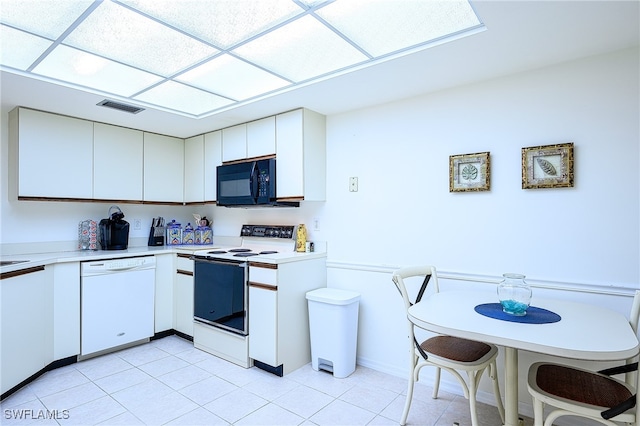 kitchen with white appliances, light tile patterned floors, and white cabinets