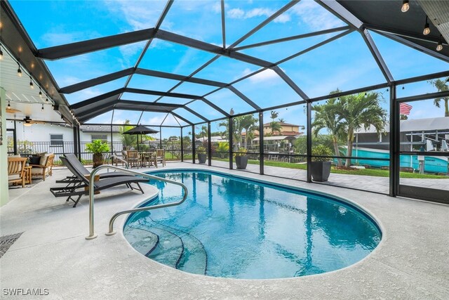 view of pool with glass enclosure and a patio area