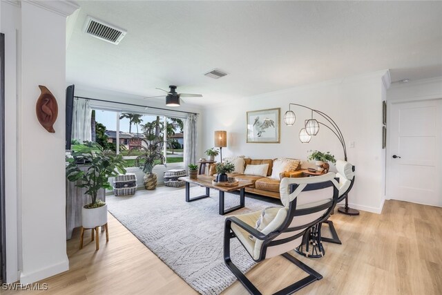 living room featuring ceiling fan, ornamental molding, and light hardwood / wood-style flooring