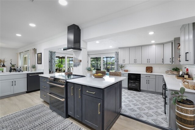 kitchen with gray cabinets, wall chimney range hood, beverage cooler, appliances with stainless steel finishes, and light hardwood / wood-style floors