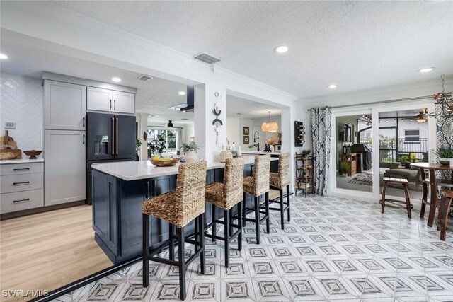 kitchen with gray cabinetry, high end refrigerator, light hardwood / wood-style floors, kitchen peninsula, and a breakfast bar area