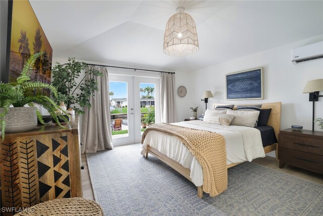 bedroom featuring french doors, light wood-type flooring, lofted ceiling, access to outside, and an AC wall unit