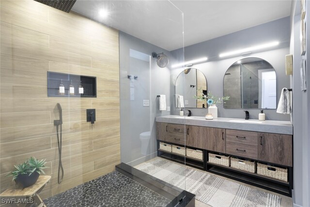 bathroom featuring vanity, toilet, and a tile shower