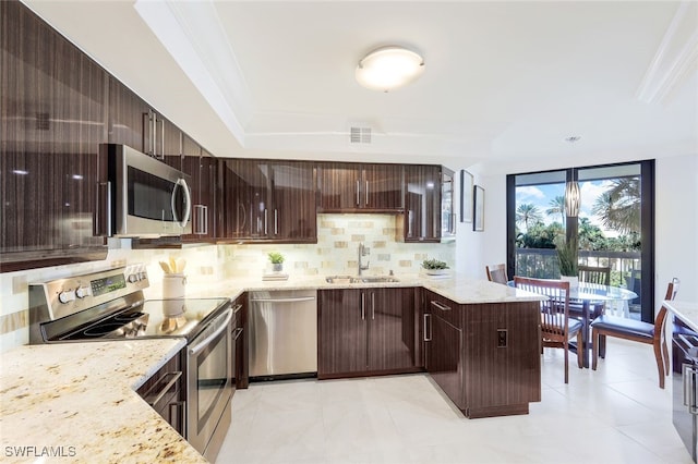 kitchen featuring appliances with stainless steel finishes, light stone counters, backsplash, and sink