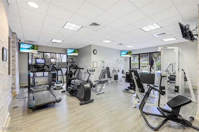 exercise room with light wood-type flooring and a paneled ceiling