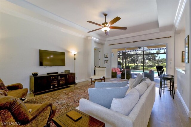 living room with ceiling fan, ornamental molding, a tray ceiling, and hardwood / wood-style floors