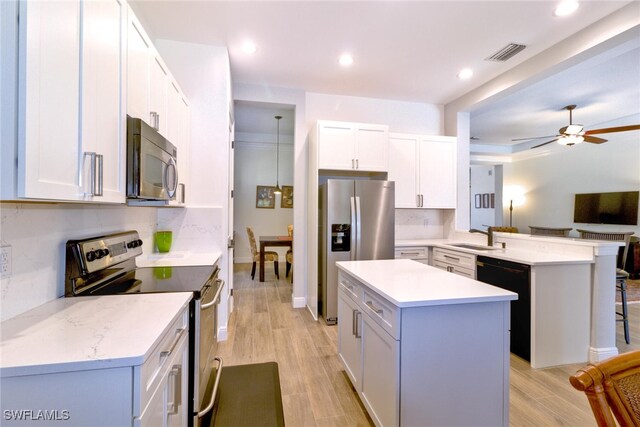 kitchen with a kitchen island, appliances with stainless steel finishes, a breakfast bar area, and white cabinets