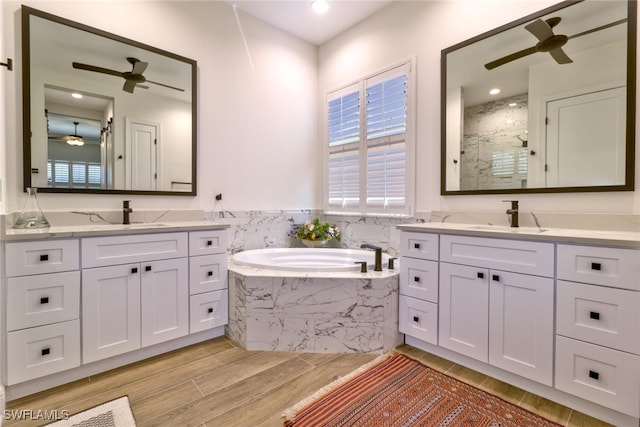 bathroom featuring ceiling fan, vanity, and plus walk in shower