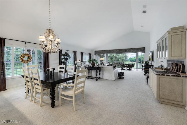 carpeted dining room featuring a healthy amount of sunlight, high vaulted ceiling, and a notable chandelier