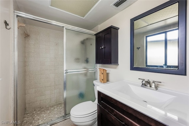 bathroom featuring a shower with shower door, toilet, and vanity