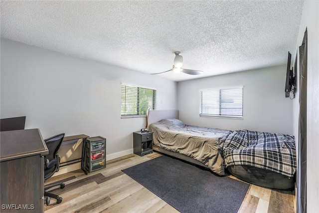 bedroom featuring multiple windows, a textured ceiling, ceiling fan, and light hardwood / wood-style floors