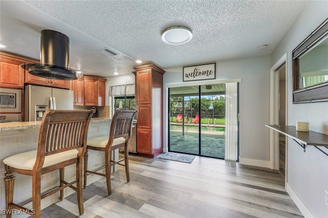 kitchen featuring a textured ceiling, stainless steel appliances, and light hardwood / wood-style floors