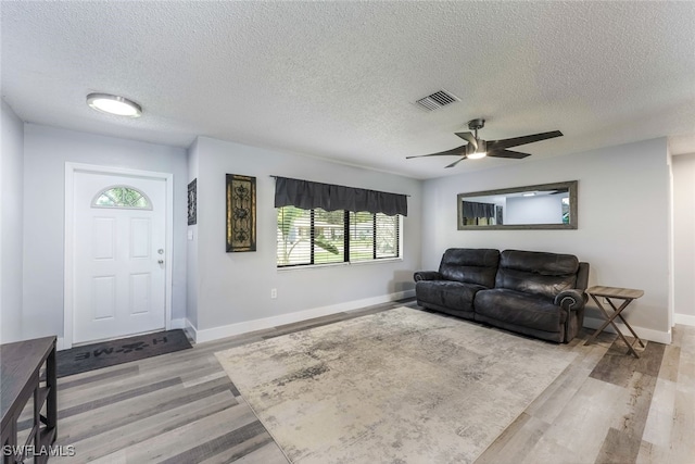 living room featuring a textured ceiling, light hardwood / wood-style flooring, and ceiling fan