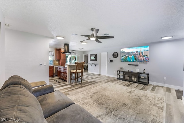 living room featuring a textured ceiling, light hardwood / wood-style flooring, and ceiling fan