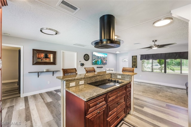 kitchen with ceiling fan, light stone countertops, light wood-type flooring, and black electric stovetop