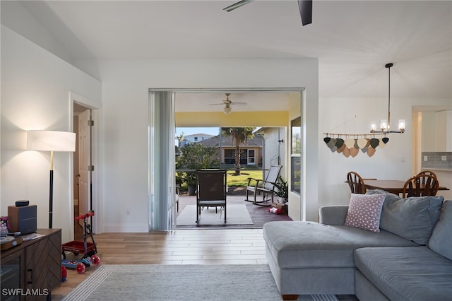 living room featuring wood-type flooring and ceiling fan with notable chandelier