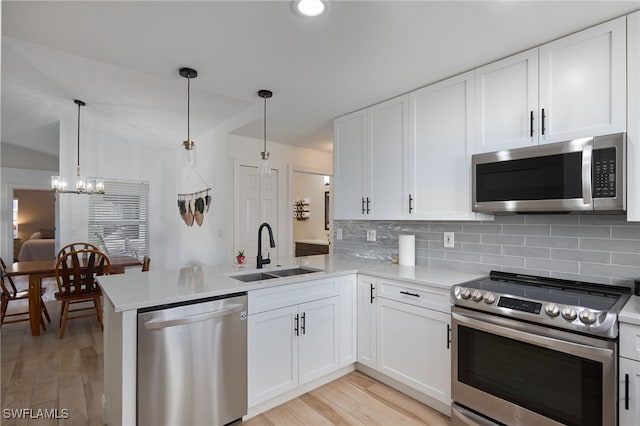 kitchen with decorative light fixtures, white cabinets, sink, and stainless steel appliances