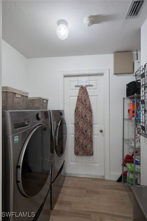 laundry area featuring washer and dryer and light hardwood / wood-style flooring