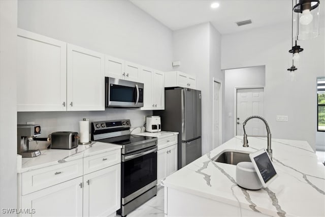 kitchen featuring pendant lighting, light stone counters, sink, and appliances with stainless steel finishes