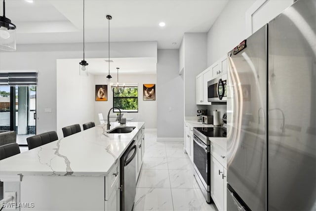 kitchen featuring pendant lighting, appliances with stainless steel finishes, an island with sink, sink, and white cabinets