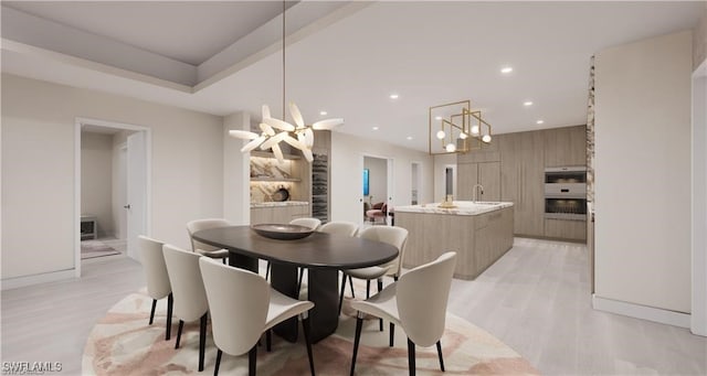 dining space with a notable chandelier, sink, and light hardwood / wood-style floors