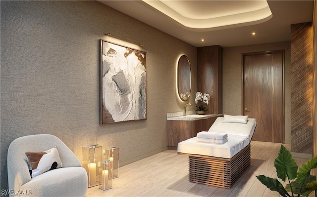 living area featuring a tray ceiling, light wood-style flooring, recessed lighting, and baseboards