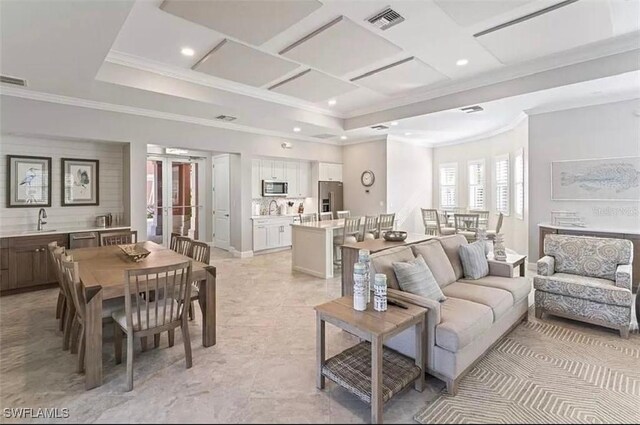 living room with ornamental molding, a raised ceiling, and sink