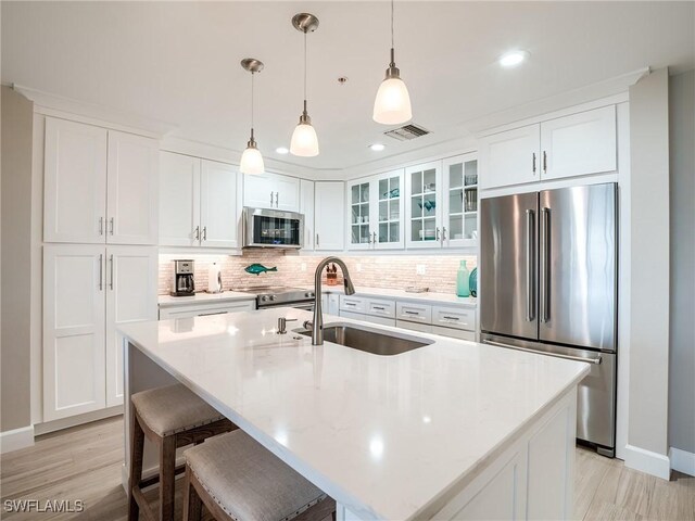 kitchen with an island with sink, light hardwood / wood-style flooring, sink, and appliances with stainless steel finishes