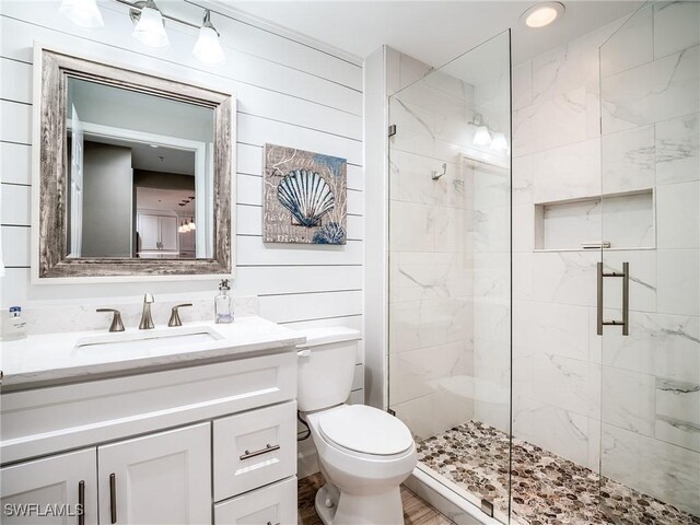 bathroom with toilet, a shower with door, wooden walls, and vanity