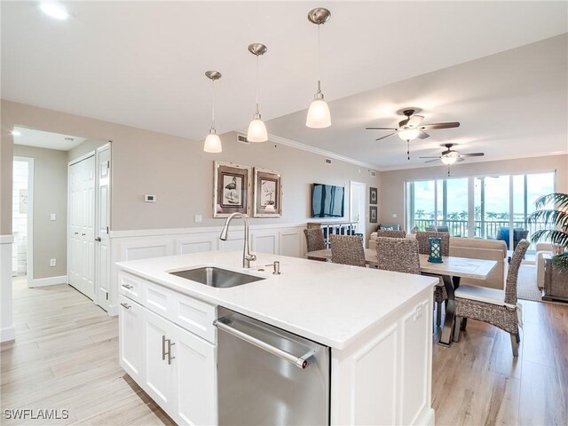 kitchen featuring a kitchen island with sink, stainless steel dishwasher, sink, ceiling fan, and light wood-type flooring