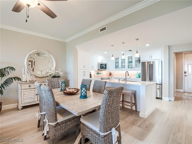 dining space with ornamental molding, light hardwood / wood-style flooring, ceiling fan, and sink