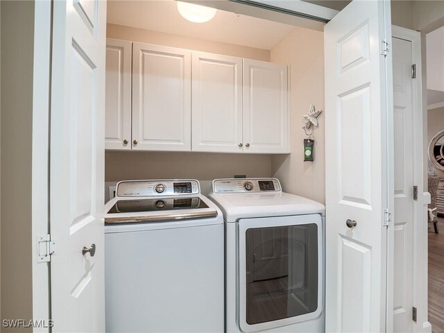 washroom featuring hardwood / wood-style flooring, cabinets, and independent washer and dryer