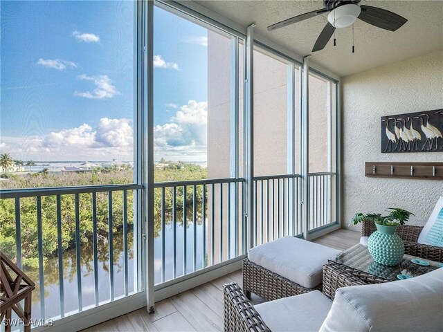 sunroom featuring a water view and ceiling fan