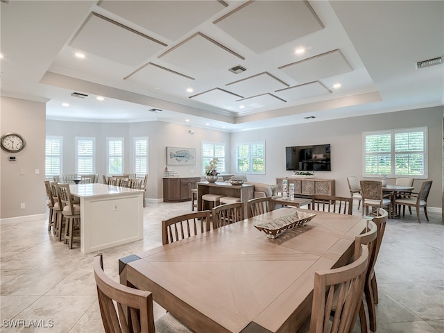 tiled dining room featuring ornamental molding and a raised ceiling