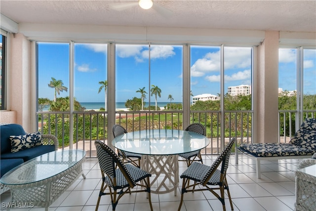 sunroom with ceiling fan, plenty of natural light, and a water view